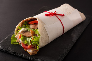 Doner kebab or shawarma sandwich on black slate background