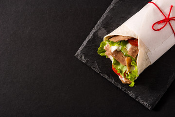 Doner kebab or shawarma sandwich on black slate background. Top view. Copy space
