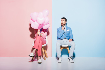 woman holding balloons and shocked man on pink and blue background