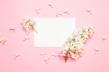 Top view minimal composition with white flower lilac branch and empty sheet of paper template on a pink background with place for text