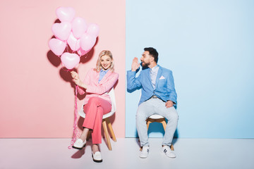 smiling woman holding balloons and handsome man on pink and blue background