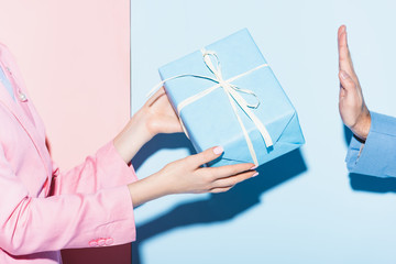 cropped view of woman giving present to man on pink and blue background