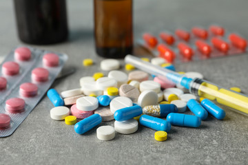 Medicines and syringe on grey table, closeup and space for text