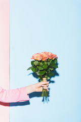 cropped view of woman holding bouquet on pink and blue background