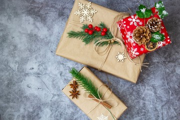 Christmas gift decorated with fir branches with cones, red berries and snowflakes
