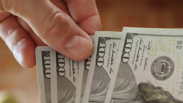 One hundred dollar bills close up. A man counts his money. Currency exchange and movement. Business and finance.