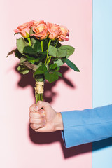 cropped view of man holding bouquet on blue and pink background