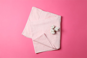 Pink towel and cotton on color background, top view