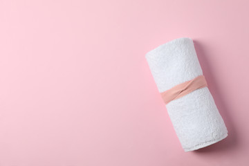 Rolled white towel on pink background, space for text