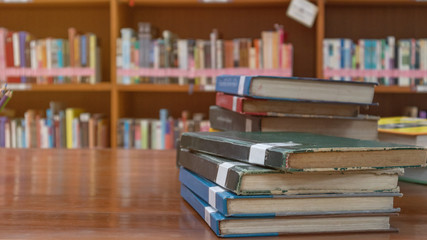 Books stack on table with book shelf background in library room education zone, education and knowledge concept.