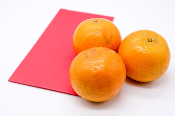 Close up and Top view of Chinese new year festival concept, three oranges, two red packets isolated on white background.