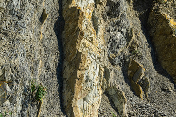 Striped natural texture of stones and rock fragments on Caucasus mountains on Black Sea coast in Olginka as original texture background. Brown, yellow, gray colored stone. Nature concept for design