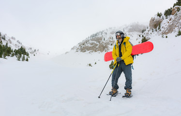 A sporty man putting on his snowshoes to start a snowy mountain excursion.