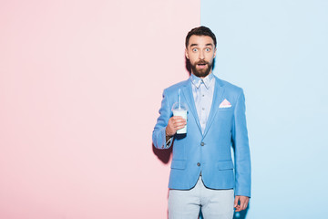 shocked man holding cocktail on pink and blue background