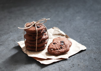 Chocolate chip cookies with dark chocolate slices with milk and coffee on a dark gray background