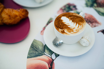 A cup of fragrant tasty cappuccino on the table in the morning at breakfast.