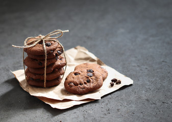 Chocolate chip cookies with dark chocolate slices with milk and coffee on a dark gray background