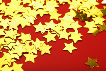 A scattering of Golden stars on red background. The concept of greeting cards, headlines and web site.