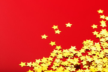 Gold stars on red background. The concept of greeting cards, headlines and web site. A scattering of Golden stars