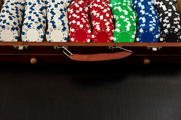 Many poker chips in a suitcase isolated on a black background. Poker