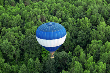 big colorful hot air balloon flying high over forest