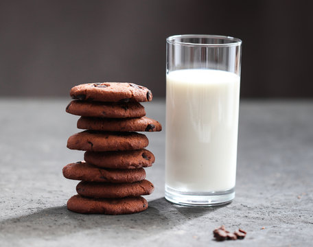 Chocolate chip cookies with dark chocolate slices with milk and coffee on a dark gray background