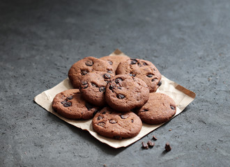 Chocolate chip cookies with dark chocolate slices with milk and coffee on a dark gray background