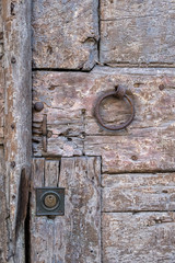 Old wooden door, rusty metal clusters and a ring. Close-up.