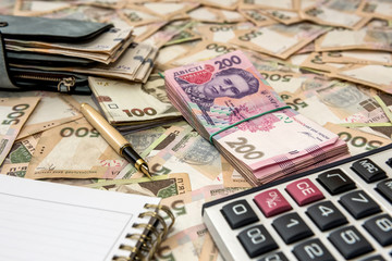 Empty notepad, full wallet of money with calculator on Ukrainian money backgrounds. 500 banknotes. Hryvnia (UAH). Top view
