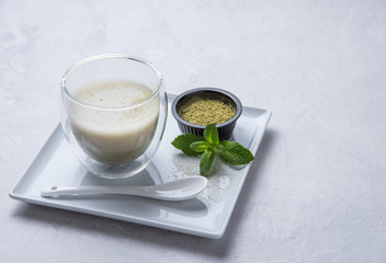 green matcha tea in transparent glass on white background