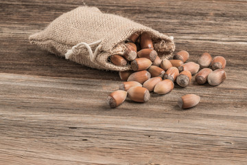 raw hazelnuts in a burlap sack on wooden table