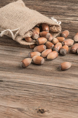 raw hazelnuts in a burlap sack on wooden table