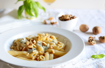 Il concetto di cibo italiano. Primo piano della pasta del penne con gorgonzola formaggio e le noci sul piatto bianco - obrazy, fototapety, plakaty