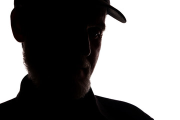 Old man in peaked cap, side view - dark close-up silhouette