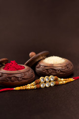 Raksha Bandhan background with an elegant Rakhi, Rice Grains and Kumkum. A traditional Indian wrist band which is a symbol of love between Brothers and Sisters.