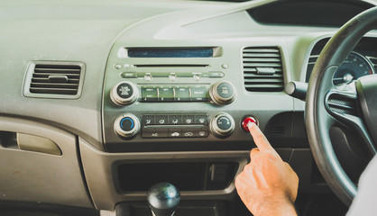 Fototapeta premium Finger male pressing a push button emergency lights in his car. Safety first insurance concept