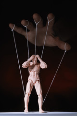 Concept of control. Marionette in human hand. Objects are colored on red and blue light.