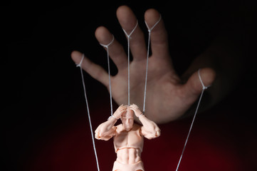 Concept of control. Marionette in human hand. Objects are colored on red and blue light. - obrazy, fototapety, plakaty