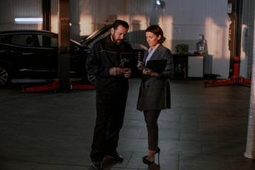 Obraz premium Service auto center mechanic have a conversation with the customer woman they sign the papers