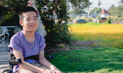 Asian special child on wheelchair smiling on his face with flower fields background, Travel on a holiday with his father, Life in the education age of disabled children, Happy disabled kid concept.