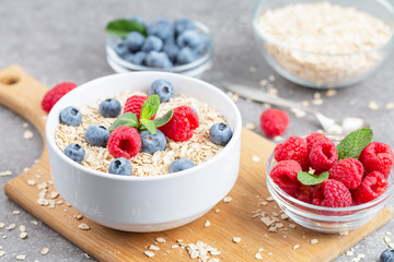 Healthy breakfast - oatmeal with fresh berries in a bowl. Oatmeal porridge with blueberries, raspberries and mint.