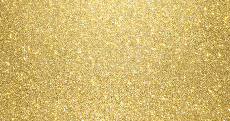 Gold glitter background with sparkling texture. Golden shimmering light, stars sequins sparks and glittering glow foil background