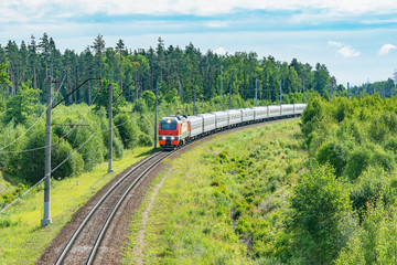 Obraz premium Passenger train approaches to the station at summer morning time.