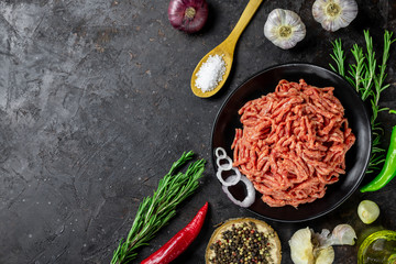 Minced meat. Shredded meat on a black background with ingredients for cooking. Top view