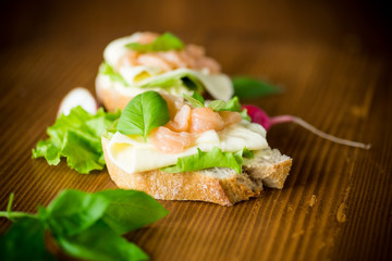 sandwich with cheese, salad leaves and red fish on a wooden