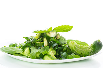 fresh salad of cucumbers and greens in a plate isolated on white