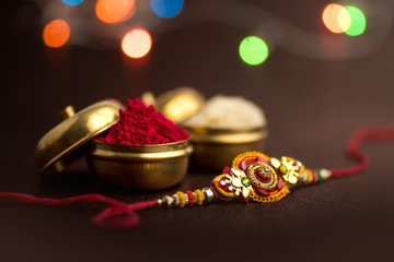 Raksha Bandhan background with an elegant Rakhi, Rice Grains and Kumkum. A traditional Indian wrist band which is a symbol of love between Brothers and Sisters.