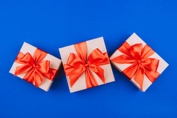 Three cardboard gift boxes with bows on blue background.