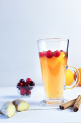 Orange and cranberry punch with orange slices and spices on a white table. Hot drinks for winter and Christmas.