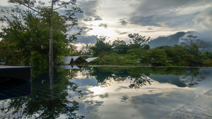 Natural reflection on the pool. Mountains and nice sky reflecting above the water surface. Khao yai, Thailand.